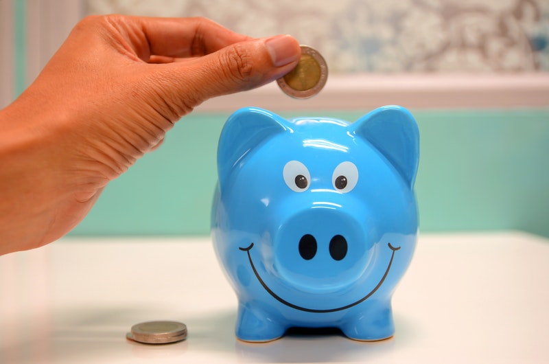 Person Putting Coin Into Piggybank